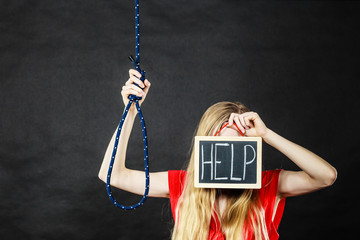 Suicidal woman holding help sign next to rope