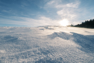 Fototapeta na wymiar Schneebedeckter Hügel bei starkem Wind der die Flocken über den Hügel fegt