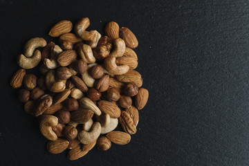 Variety of mixed nuts - almond, hazelnuts and cashew - on the dark slate background with copy space. Top view. Toned