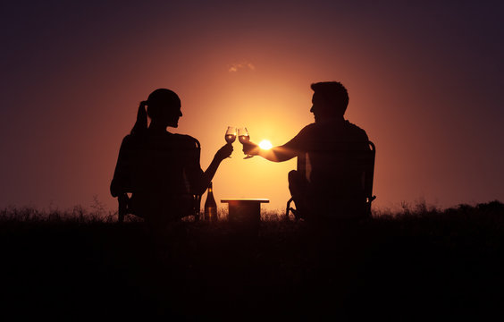 Romantic couple. Man woman relaxing outdoors, enjoying a glass of wine and beautiful sunset