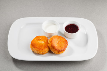 Carrot pancakes with jam and sour cream on white plate