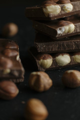 Chocolate bar pieces and nuts on dark background with copy space. Chocolate background. Toned