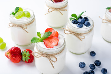 Fresh yogurt with berries in glass jars. Dairy products. Healthy food, dieting and breakfast concept. Close up