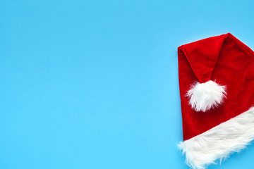 Christmas card. A bright red Santa Claus hat lies folded on a blue background. Background for your text and design                               
