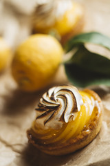 Lemon pie on the table with citrus fruits. Traditional french sweet pastry tart. Delicious, appetizing, homemade dessert with lemon cream. Copy space, closeup. Selective focus. Toned