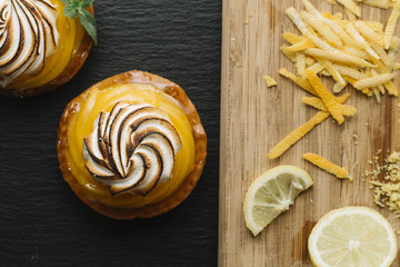 Lemon pie on the table with citrus fruits. Traditional french sweet pastry tart. Delicious, appetizing, homemade dessert with lemon cream. Copy space, closeup. Selective focus. Toned