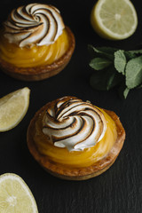 Lemon pie on the table with citrus fruits. Traditional french sweet pastry tart. Delicious, appetizing, homemade dessert with lemon cream. Copy space, closeup. Selective focus. Toned