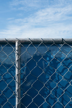 Chain-link fence in front of blue plastic tarp at construction site