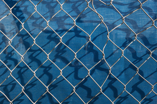Chain-link fence in front of blue plastic tarp at construction site