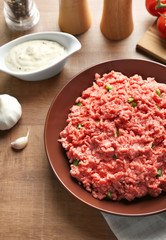 Plate with fresh raw minced meat on table