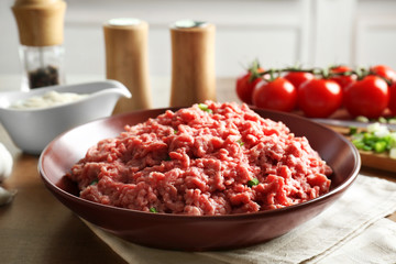 Plate with fresh raw minced meat on table