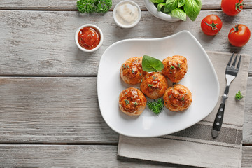 Plate with delicious meatballs and sauces on wooden table