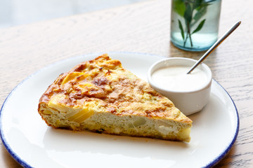 Scrambled eggs Spanish tortilla with potatoes. The slice lies on the plate