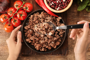 Woman stirring cooked minced meat in kitchen