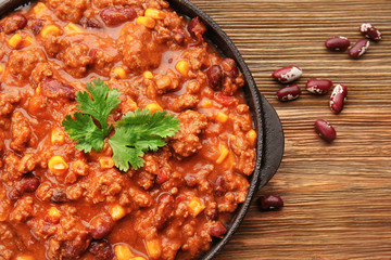 Chili con carne in frying pan on wooden background