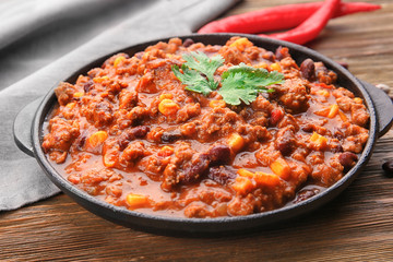 Chili con carne in frying pan on wooden background