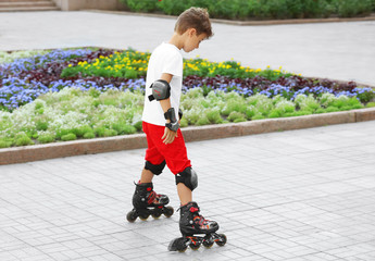 Cute boy rollerskating in park