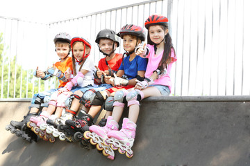 Cute kids on rollers sitting in skate park © Africa Studio