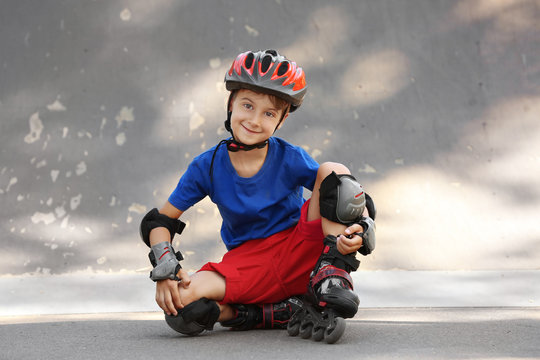 Cute boy on rollers sitting in skate park