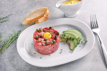 Delicious steak tartare with yolk and capers on plate