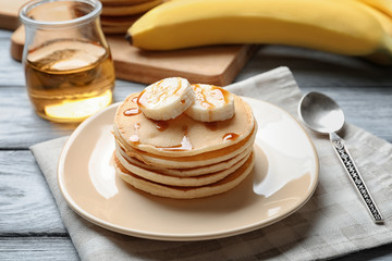 Plate with yummy banana pancakes on wooden table