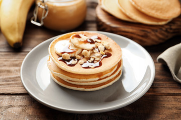 Plate with yummy banana pancakes on wooden table