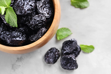 Bowl with tasty dried plums on table