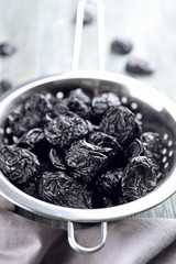 Collander with tasty dried plums on table