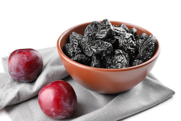 Bowl with tasty dried plums on white background