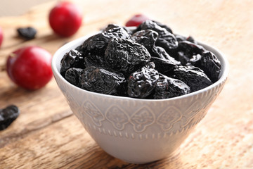 Bowl with tasty dried plums on table