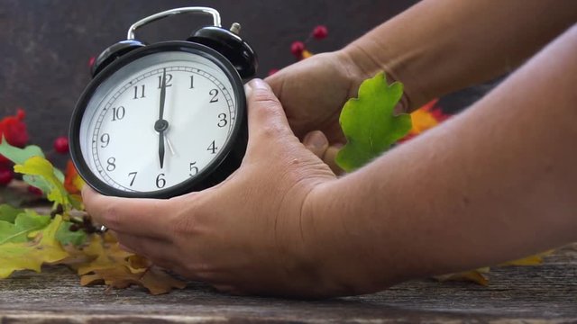 Autumn time - someones hands changing time, one hour back on alarm clock