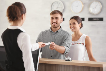 Young couple receiving key card from hotel room at reception