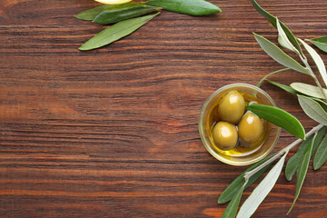 Glass bowl with olive oil on wooden table