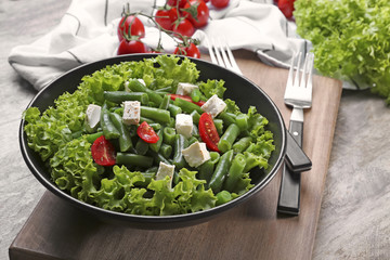 Bowl with delicious green beans salad on wooden table