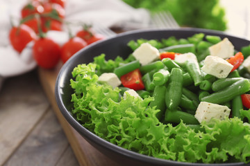 Bowl with delicious green beans salad on wooden table, closeup