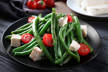 Plate with delicious green beans salad on wooden table, closeup