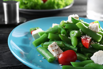 Plate with delicious green beans salad on wooden table, closeup