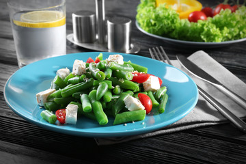 Plate with delicious green beans salad on wooden table