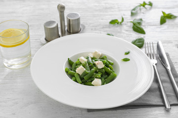 Plate with delicious green beans salad on wooden table