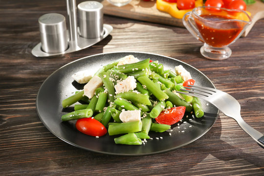 Plate with delicious green beans salad on wooden table