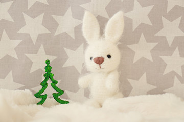 Small bunny toy and decorative Christmas tree on blanket