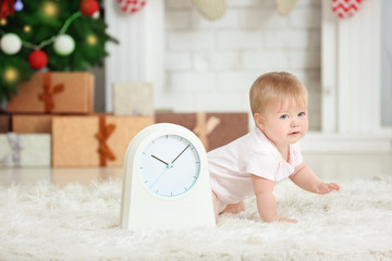 Adorable baby with clock in decorated room. Christmas countdown concept