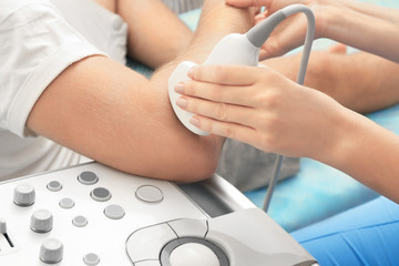 Doctor conducting ultrasound examination of patient's elbow in clinic
