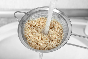 Washing raw rice with water in kitchen