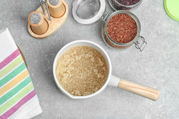 Washing raw rice in saucepan on kitchen table