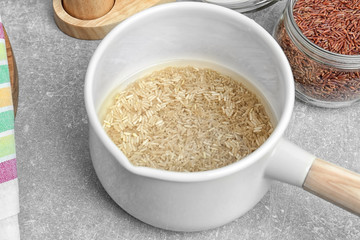 Washing raw rice in saucepan on kitchen table