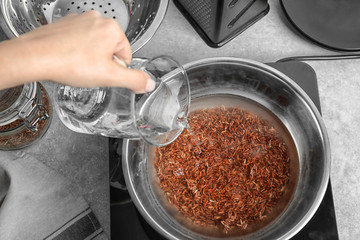 Woman pouring water into bowl with boiling rice