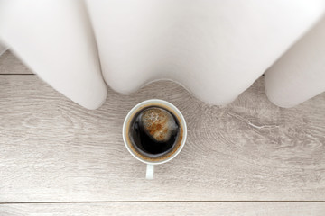 Cup of coffee on floor near curtains