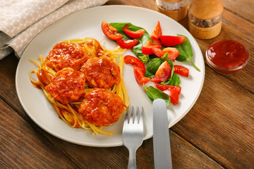 Plate with tasty sausage balls and garnish on table