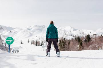 Female snowboarder in front of a beginner ski slope.